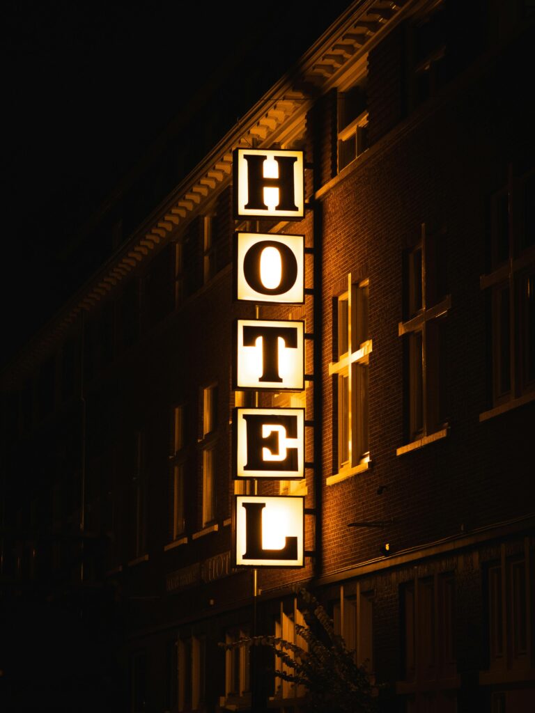 A bright hotel sign glowing on a building facade during nighttime.